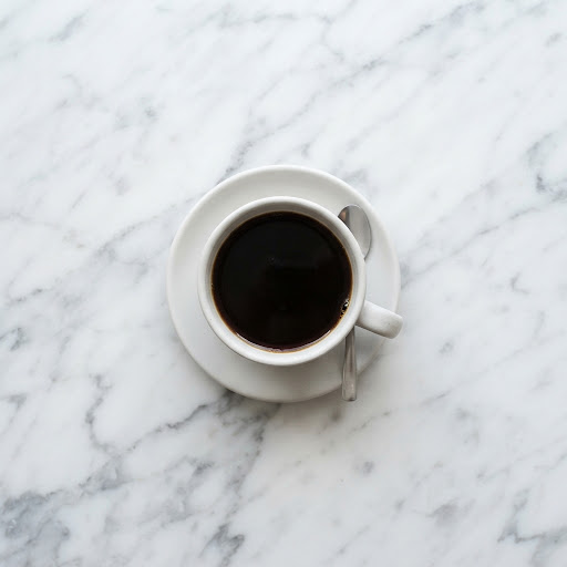 Secangkir kopi hitam di atas meja marmer putih